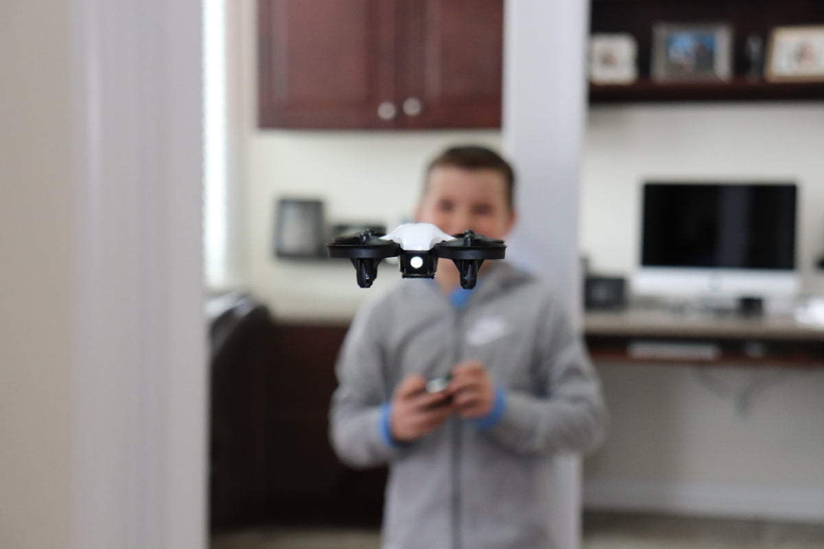 man in blue jacket holding black and gray drone