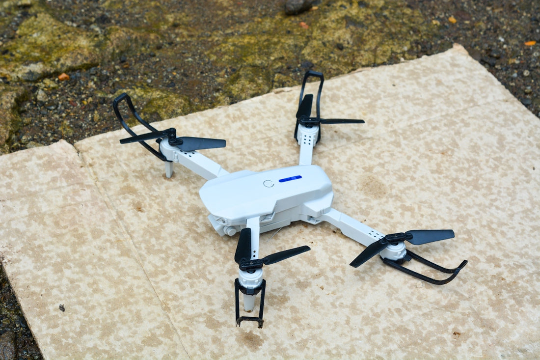 A white drone rests on a textured surface.