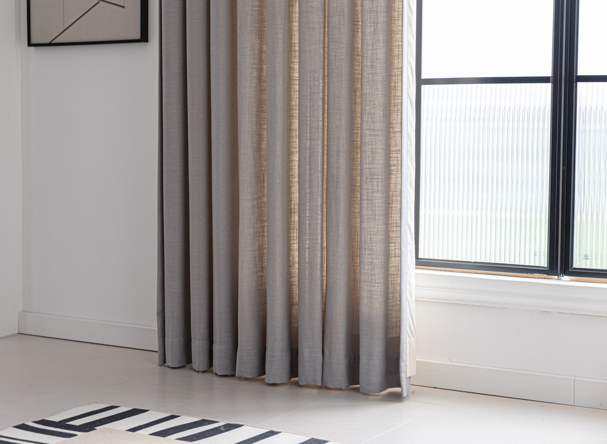 Curtains frame a window in a bright room.