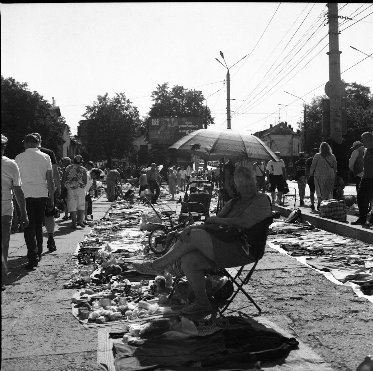 Woman sitting at outdoor market under umbrella