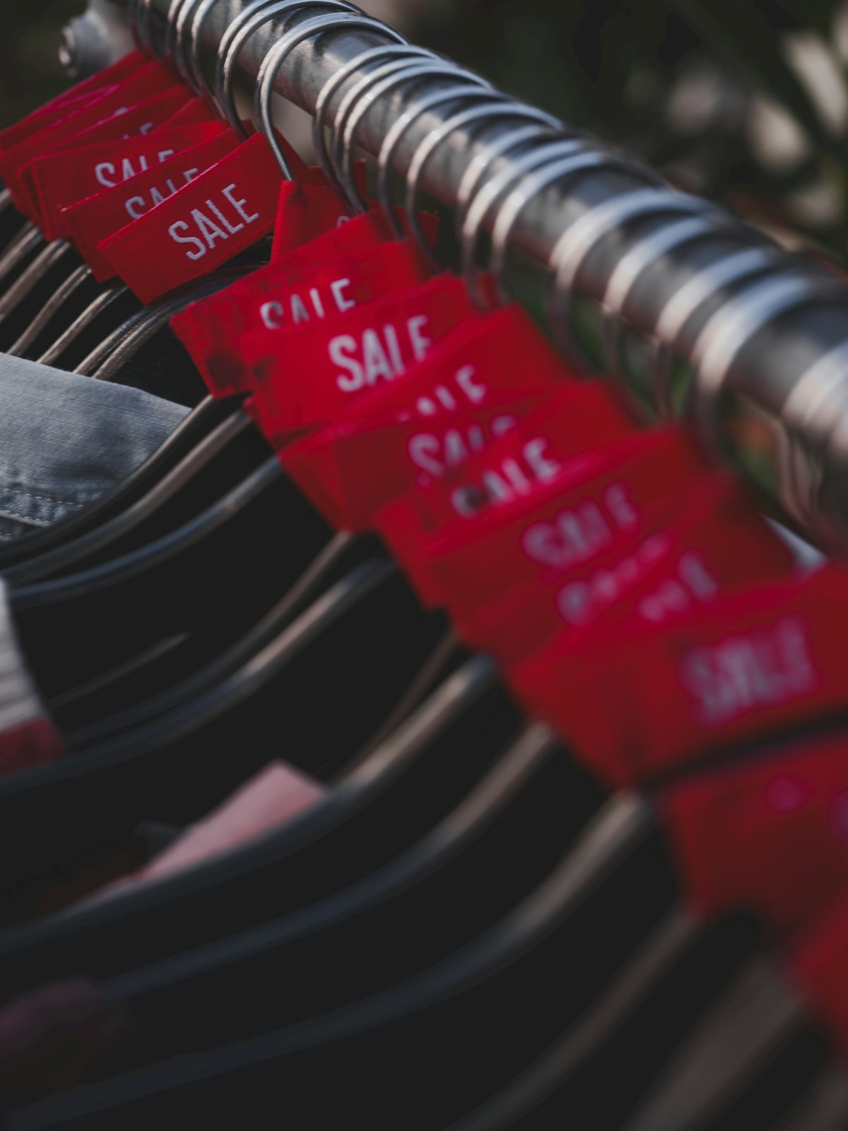 Red sale tags hanging on a clothing rack
